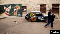 A man walks past graffiti painted on a wall and car inside a 15th-century complex built by Mameluk Sultan al-Ashraf Qaitbey in Cairo's City of the Dead, Egypt, Feb. 13, 2017.