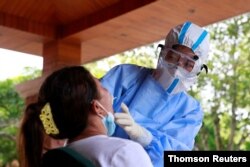 Medical worker in protective suit collects a swab sample from a woman for nucleic acid testing in the border city of Ruili, Sep. 16, 2020.