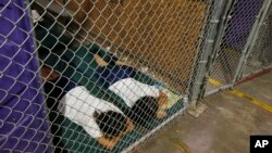 FILE - Two female detainees sleep in a holding cell, as the children are separated by age group and gender, as hundreds of mostly Central American immigrant children are being processed and held at the U.S. Customs and Border Protection Nogales Placement Center in Nogales, Arizona, June 18, 2014.