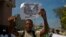 FILE - A demonstrator participates in a November 2012 anti-government march shouts while carrying a flier with images of Clifford Brandt, son of a wealthy Haitian businessman who heads an alleged kidnapping ring, and Olivier Martelly, son of Haiti's president.