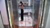 A woman stands in an elevator with markers on the floor for social distancing measures in a shopping mall amid concerns over the spread of the coronavirus in Bangkok, Thailand, March 20, 2020. 