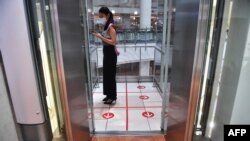 A woman stands in an elevator with markers on the floor for social distancing measures in a shopping mall amid concerns over the spread of the coronavirus in Bangkok, Thailand, March 20, 2020. 