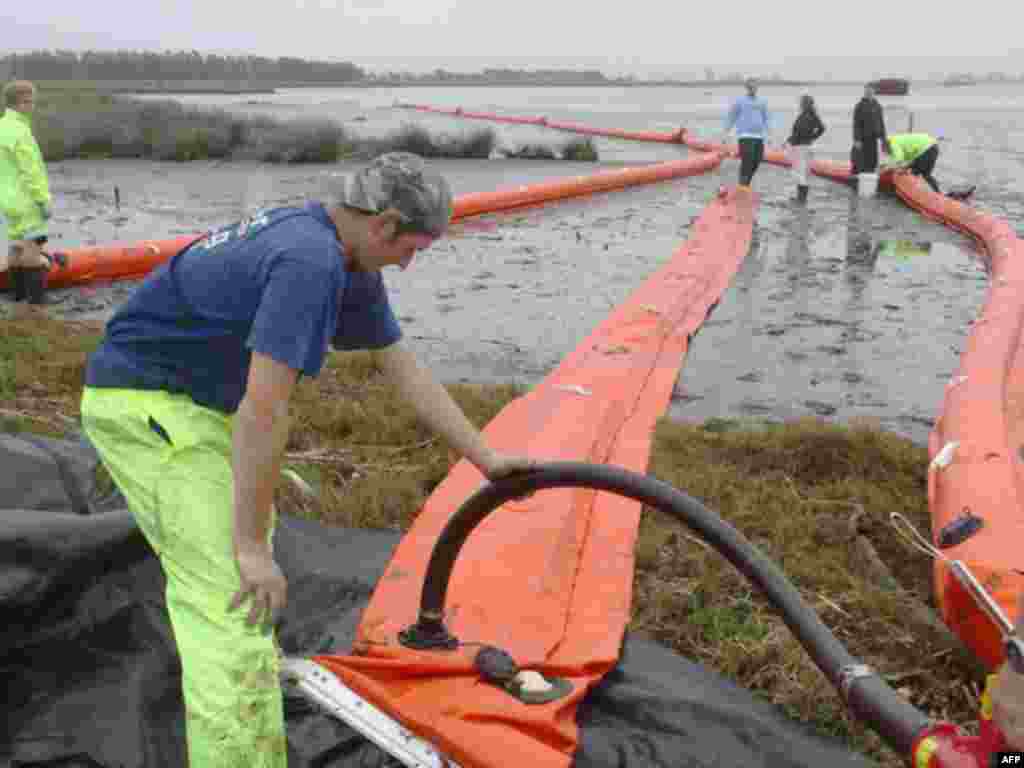 Oil booms are prepared at the Maketu Estuary in the Bay of Plenty, on New Zealand's North Island October 13, 2011, Oil tanks on the 47,230-tonne Liberian-flagged Rena threatening to break in half off the New Zealand coast have survived a pounding by heavy