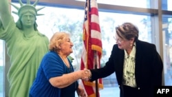 New US citizen Tamam Shanazarian, left, shakes hands with Nancy Alby, field director of USCIS Los Angeles, during a naturalization ceremony ahead of World Refugee Day by the US Citizenship and Immigration Services on June 17, 2021 in Los Angeles.