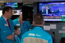 Traders at the New York Stock Exchange listen to President Donald Trump's televised White House news conference, March 17, 2020.