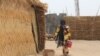 Une femme porte un seau d'eau au camp informel de Yawuri, à la périphérie de Maiduguri, capitale de l'État de Borno, le 29 mars 2021. (Audu Marte/AFP)