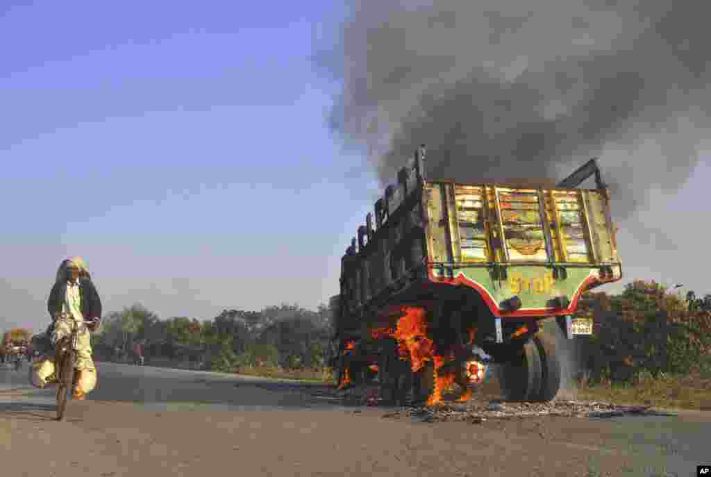 A man rides past a truck set on fire during a strike called by Jamaat-e-Islami in Rajshahi, Bangladesh, Feb. 28, 2013.