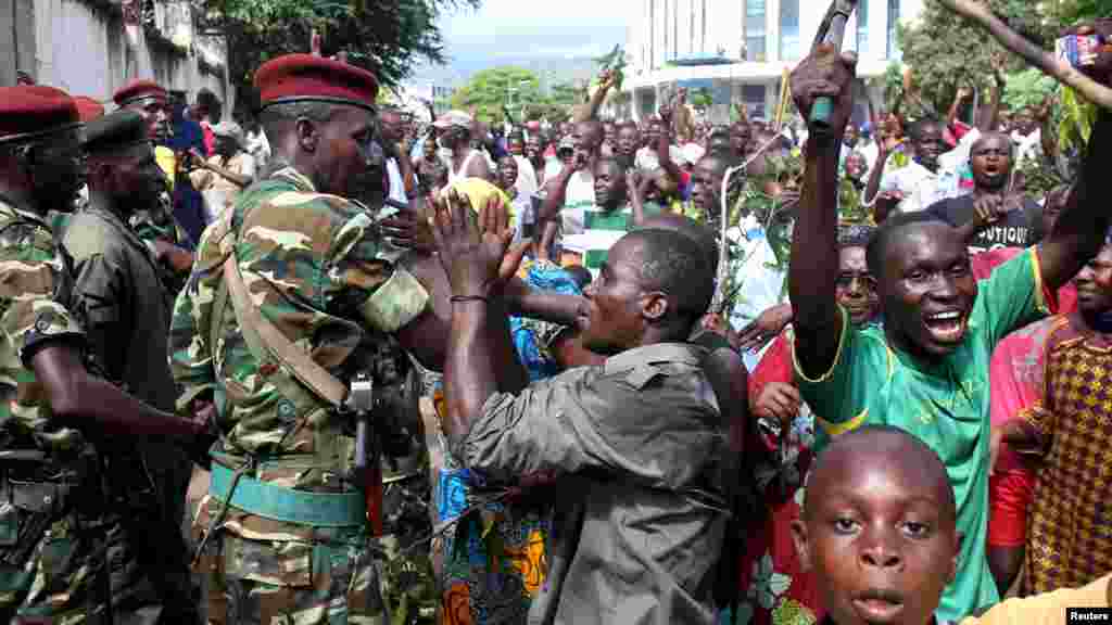 La foule salue des soldats alors qu&#39;elle célèbre après l&rsquo;annonce de la destitution du président Pierre Nkurunziza par un haut gradé de l&rsquo;armée à Bujumbura, au Burundi le 13 mai 2015.