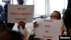FILE - Senior doctors at Parirenyatwa General Hospital, Zimbabwe's biggest medical center, hold placards during a demonstration to protest a lack of medicines, gloves and bandages in Harare, March 13, 2019.