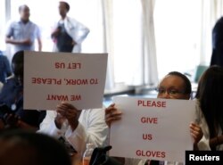FILE - Senior doctors at Parirenyatwa General Hospital, Zimbabwe's biggest medical center, hold placards during a demonstration to protest a lack of medicines, gloves and bandages in Harare, March 13, 2019.