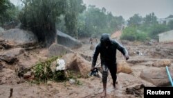 Mtu mmoja akiondoka kwenye majengo yaliyoharibiwa na Kimbunga Freddy huko Chilobwe, Blantyre, Malawi, Machi 13, 2023. REUTERS/Eldson Chagara.