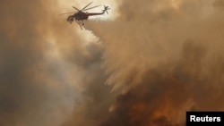 Sebuah helikopter menyiramkan air di kebakaran hutan yang dipicu angin kencang di California, 9 Oktober 2017. 