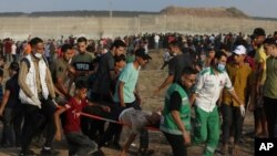 پزشکان فلسطینی در حال انتقال یک فرد زخمی‌شده در جریان تظاهرات روز شنبه ٣٠ مرداد ۱۴۰۰ در نزدیکی مرز غزه و اسرائیل