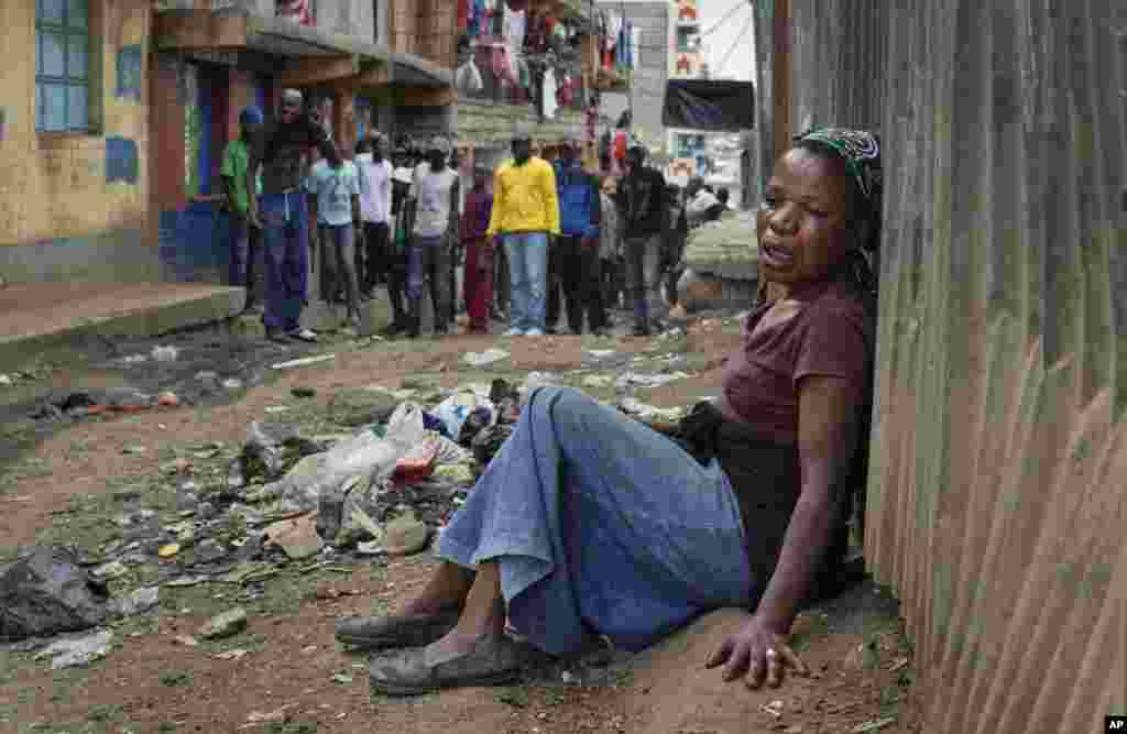  A relative weeps on the ground in an alleyway near the body of a man who had been shot in the head as the angry crowd shouts at the police, in the Mathare slum of Nairobi, Kenya. Kenya's election took an ominous turn as violent protests erupted in the capital.