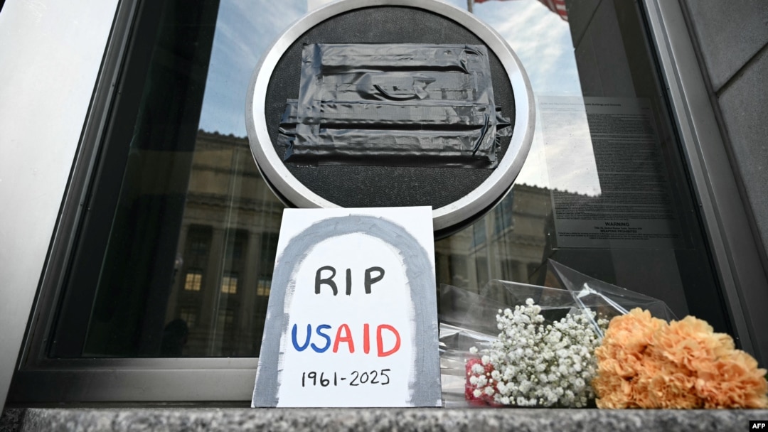 FILE - Tributes are placed beneath the covered seal of the U.S. Agency for International Development (USAID) at its headquarters in Washington, Feb. 7, 2025.