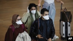 Passengers wearing masks arrive at the Ben Gurion Airport near Tel Aviv, Israel, March 10, 2020. Israel will quarantine anyone arriving from overseas for 14 days, a decision coming barely a month before Easter and Passover. 