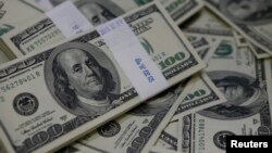 U.S. $100 bills are shown, Aug. 2, 2013. Almost 20 people were arrested March 1, 2017, as authorities put an end to a complex international fraud and money laundering ring.