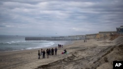 ARCHIVO - Varias personas caminan cerca del muro fronterizo entre Estados Unidos y México el sábado 25 de enero de 2025 en Tijuana, México. (Foto AP/Ethan Swope).