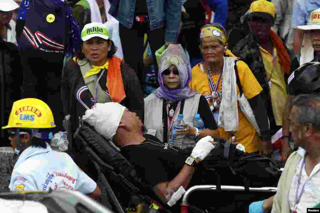 Anti-government protesters watch as an injured man is taken away from a clash site at a police compound housing a government security group, in the north of Bangkok, May 9, 2014.