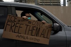 ​ Un manifestante con un cartel que se lee en español “Detención de ICE = Sentencia de muerte COVID-19 '' pasa por el Centro de Detención de Otay Mesa, un centro de detención federal de ICE. 11 de abril de 2020. ​