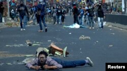 Seorang peserta demo terjatuh di jalan saat bentrokan antara pengunjuk rasa mahasiswa dengan polisi di Makassar, Sulawesi Selatan, 24 September 2019. (Foto: Reuters)