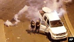 FILE - Lebanese reporter Joyce Akiki, L, runs from tear gas during an anti-government protest in Beirut, Oct. 18, 2019.