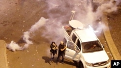 FILE - Lebanese reporter Joyce Akiki, L, runs from tear gas during an anti-government protest in Beirut, Oct. 18, 2019. Journalists are facing wide-ranging harassment and obstacles due to their reporting on anti-government protests.