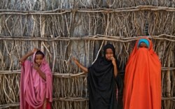 In this Tuesday, Dec. 19, 2017 file photo, Somali refugee girls stand by the fence surrounding their hut at Dadaab refugee camp in northern Kenya.