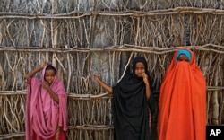FILE - Somali refugee girls stand by the fence surrounding their hut at Dadaab refugee camp in northern Kenya, Dec. 19, 2017.