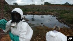 FILE - Waste removal experts work to remove hazardous black sludge from a garbage dump in Abidjan, Ivory Coast.