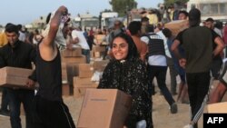 FILE—Palestinians carry boxes of humanitarian aid after rushing the trucks transporting the international aid from the US-built Trident Pier near Nuseirat in the central Gaza Strip on May 18, 2024, amid the ongoing conflict between Israel and Hamas.