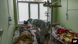 Dr. Oleh Hornostayev speaks to a coronavirus patient at a hospital intensive care unit in Stryi, Ukraine, on Tuesday, Sept. 29, 2020. (AP Photo/Evgeniy Maloletka)