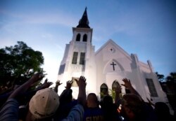 FILE - Men of Omega Psi Phi Fraternity Inc. lead people in prayer outside the Emanuel AME Church, after a memorial service for nine people killed by Dylann Roof in Charleston, S.C., June 19, 2015.